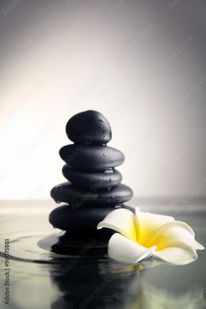 Composition of plumeria flower and pebbles pile on grey background Composition of plumeria flower and pebbles pile on grey background