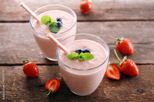 Fresh strawberry yogurt with berries around on wooden background