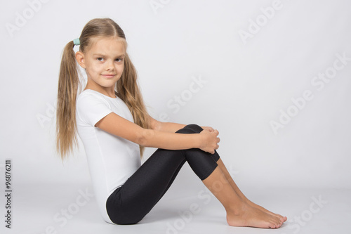 Gymnast six years sitting hugging her knees legs
