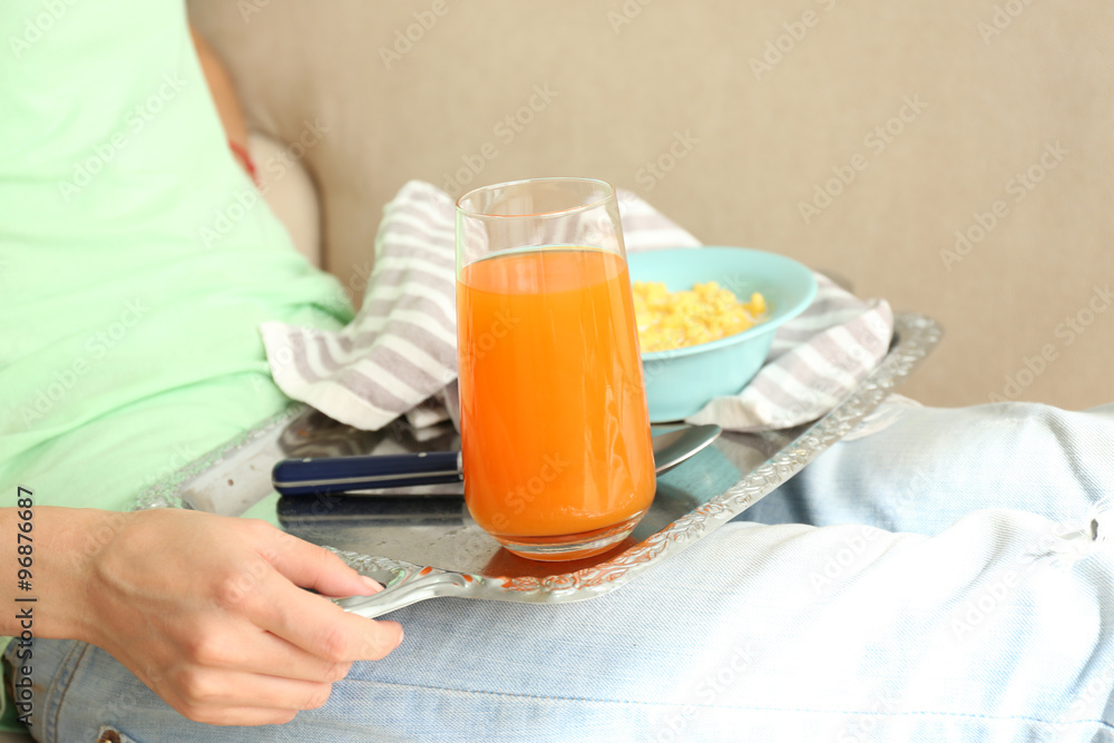 A girl with a tray having lunch on a sofa, close-up A girl with a tray having lunch on a sofa, close-up