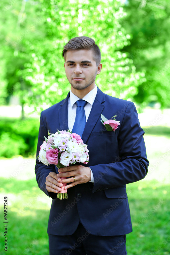 Groom holding wedding bouquet outdoors Groom holding wedding bouquet outdoors
