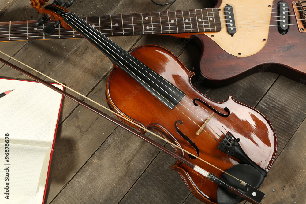 Fototapeta premium Electric guitar, violin, soprano saxophone and book on wooden background