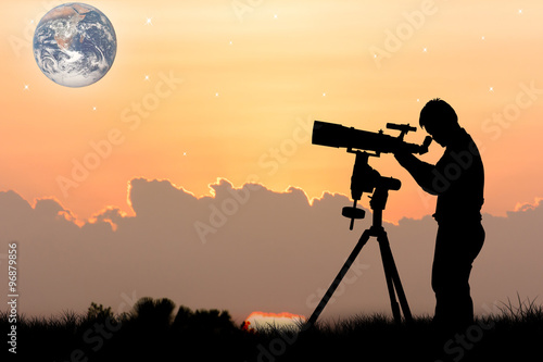 silhouette of young man looking through a telescope at night ,naza