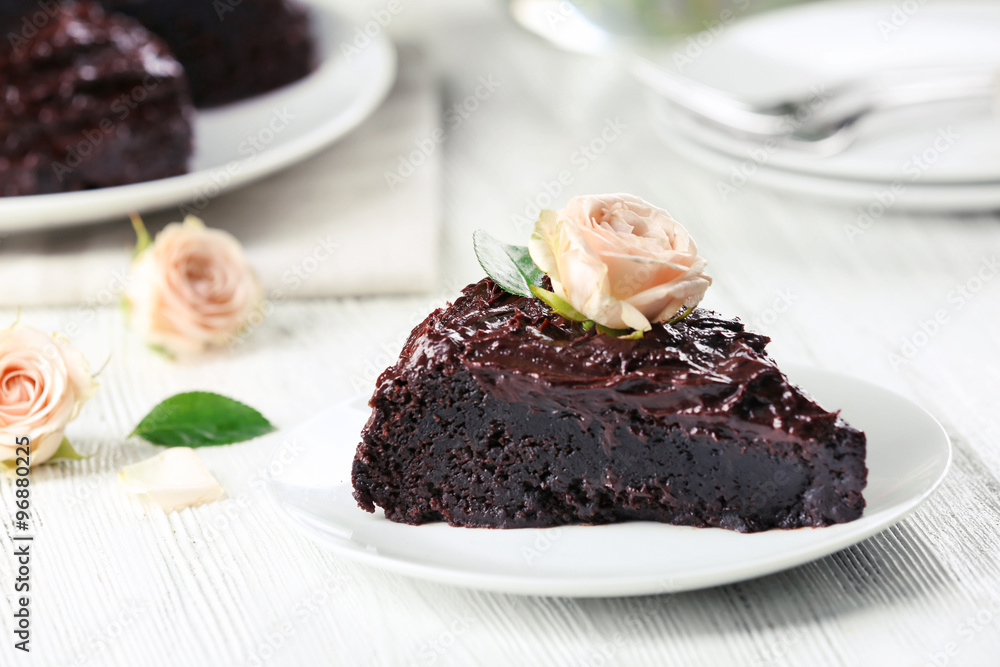 Piece of chocolate cake decorated with flowers on white wooden table Piece of chocolate cake decorated with flowers on white wooden table
