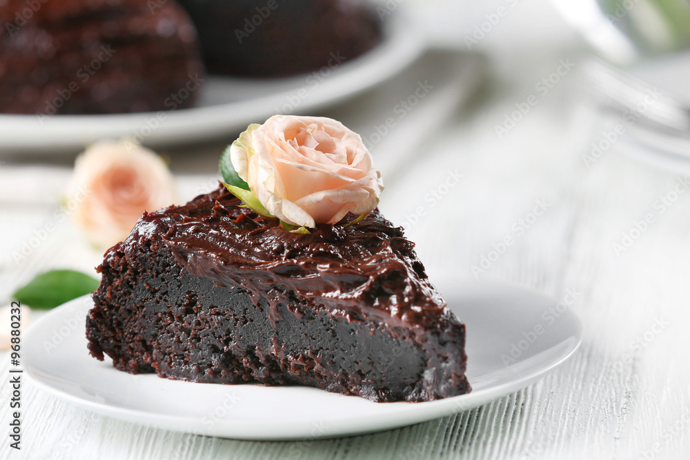 Piece of chocolate cake decorated with flowers on white wooden table Piece of chocolate cake decorated with flowers on white wooden table