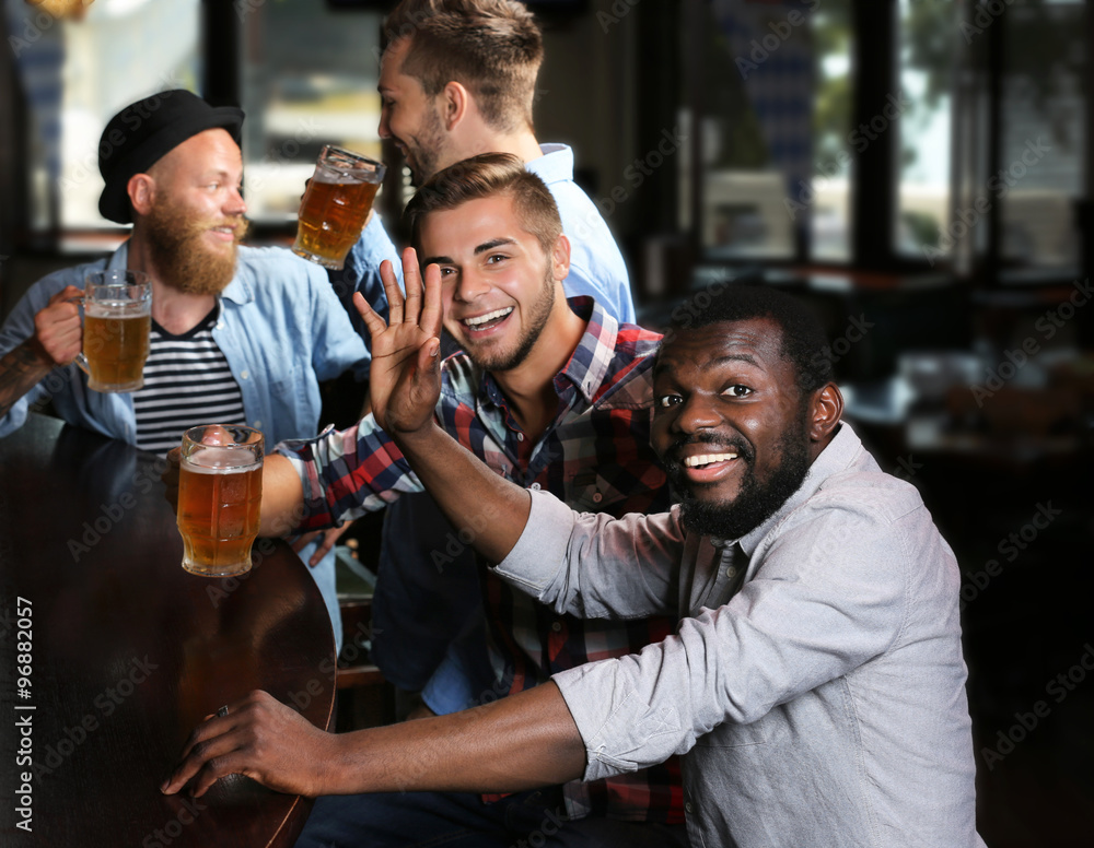 Happy friends having fun and drinking beer in pub Happy friends having fun and drinking beer in pub