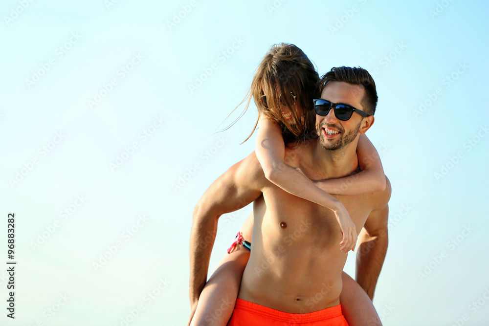 A guy carrying a girl on his back, at the beach, outdoors A guy carrying a girl on his back, at the beach, outdoors