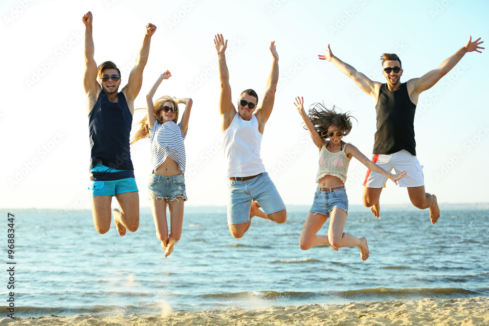 Happy friends jumping at the beach, outdoors Happy friends jumping at the beach, outdoors