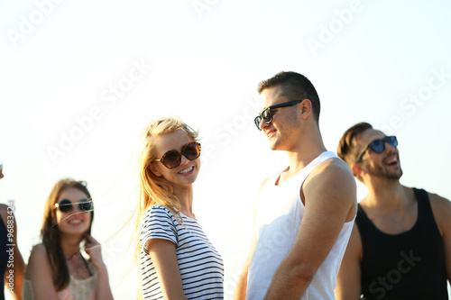 Happy couple and friends having fun at the beach, on sky background