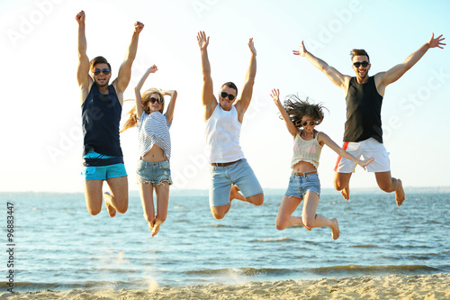 Happy friends jumping at the beach, outdoors © Africa Studio
