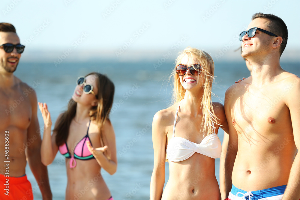 Happy couple and their playful friends relaxing at the beach, outdoors