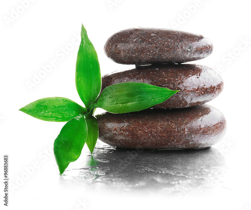 Stack of stones and a green flower on white wet background. Spa relaxation concept