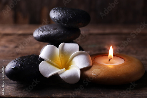 Relaxing set of fragipani flower  pebbles and alight candle on wooden background