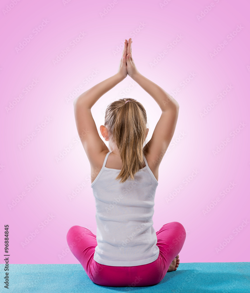 Side view of full body young female practicing Uttana Shishosana yoga pose  while lying on yellow wall on blue background stock photo
