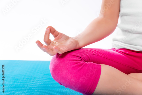Little girl sitting in yoga pose over color background.