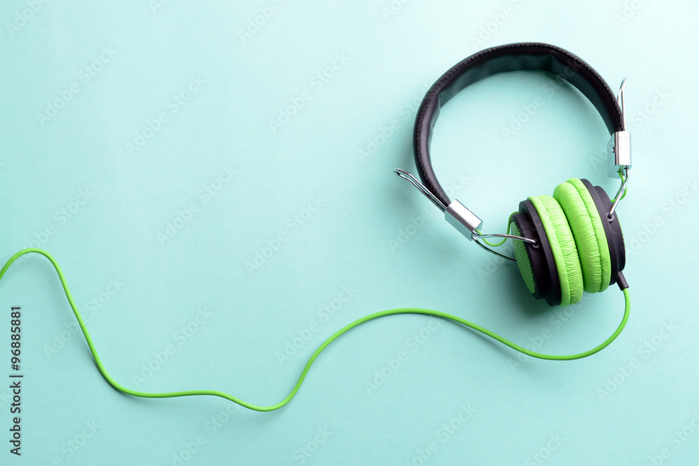 A pair of green-black headphones, on blue background A pair of green-black headphones, on blue background