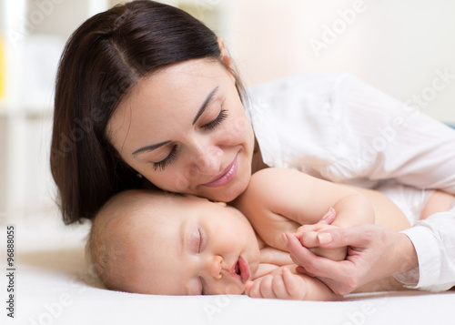 happy young mom near sleeping baby