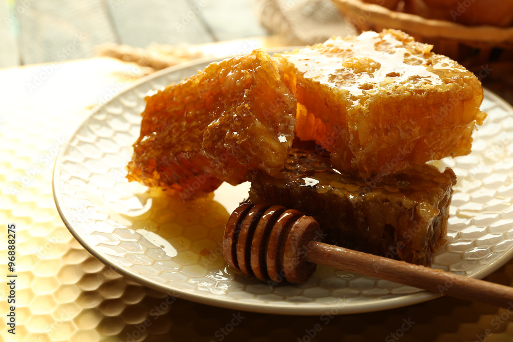 Honeycombs and wooden dipper on plate on bright background