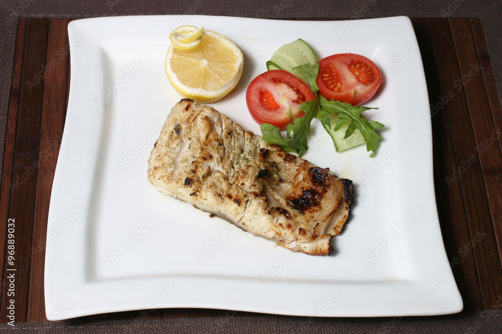 fried piece of fish in lemon juice with vegetables