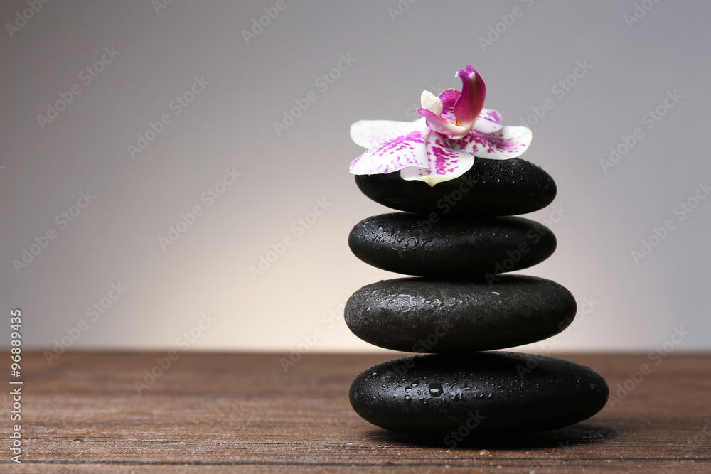 Black pebbles with orchid on wooden table Black pebbles with orchid on wooden table