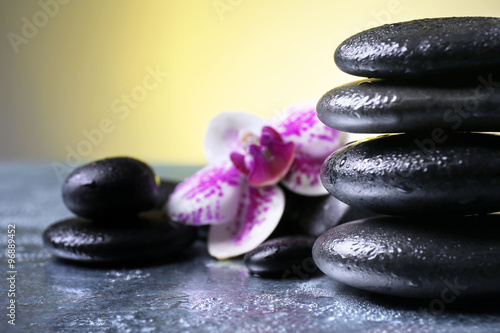 Black pebbles with orchid on grey table  close up