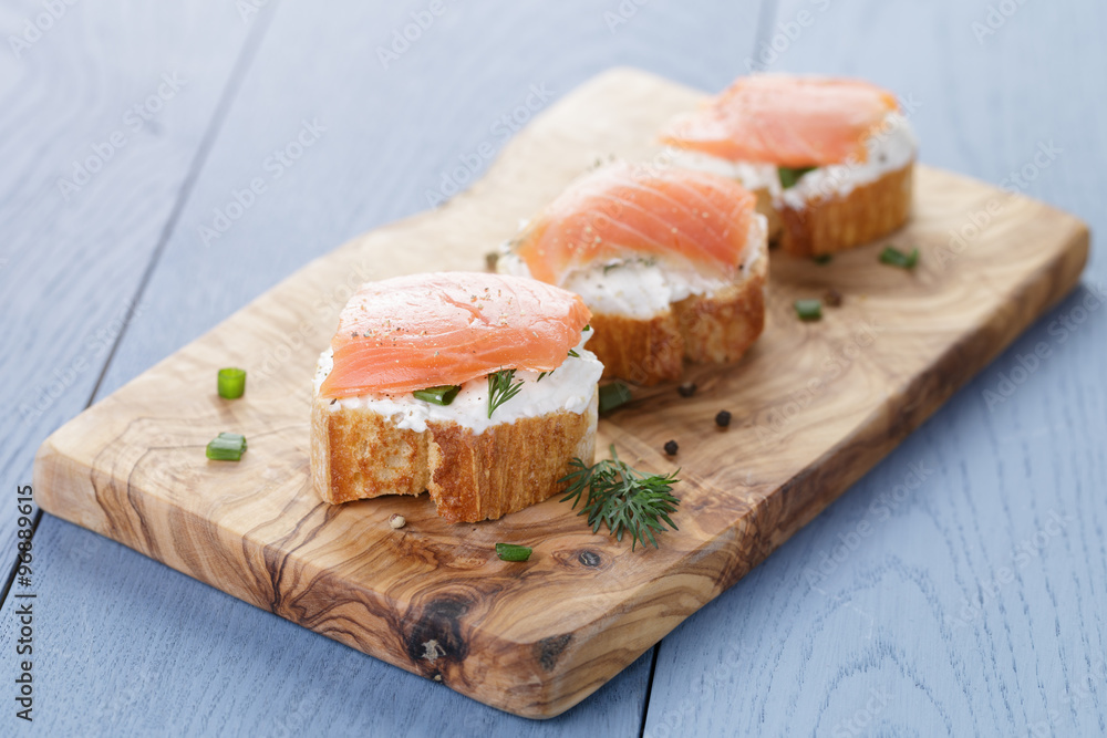 baguette slices with soft cheese and salmon on wood table baguette slices with soft cheese and salmon on wood table