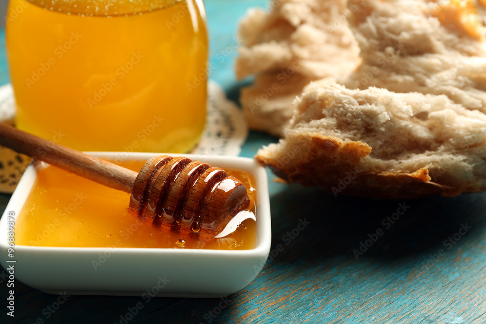 Glass jar and bowl with honey and bread on gray background Glass jar and bowl with honey and bread on gray background