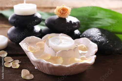 Photography Spa relaxation still life with floating candle, rose petals, and wet basalt ston
