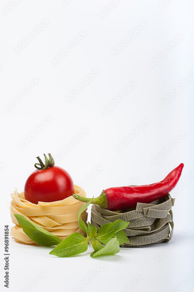 Italian pasta fettuccine nests with tomato and sharp pepper isolated on white background Italian pasta fettuccine nests with tomato and sharp pepper isolated on white background
