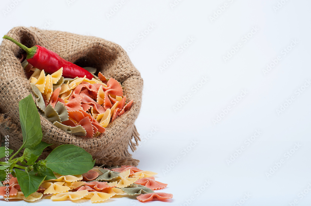 Farfalle pasta in a sack with sharp pepper isolated on white background