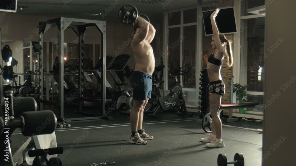 The man the weightlifter lifts a bar in a gym The man the weightlifter lifts a bar in a gym