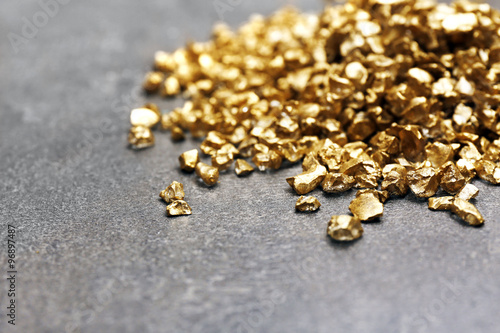 Φωτογραφία A pile of Gold nugget grains, on cement background