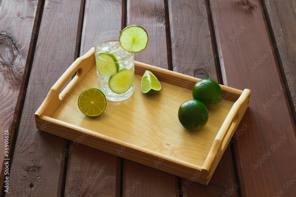 Drink on wooden tray with ice and condensation on glass