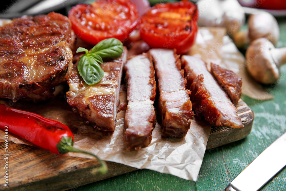 Roasted beef fillet and vegetables on cutting board, on wooden background Roasted beef fillet and vegetables on cutting board, on wooden background
