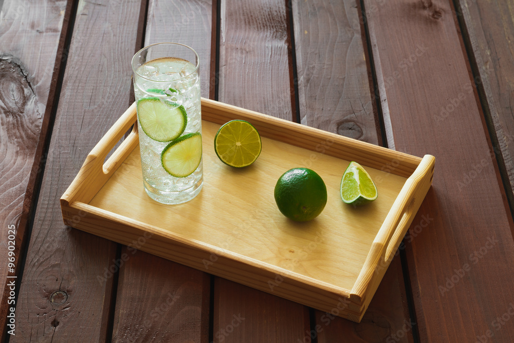 Drink on wooden tray with ice and condensation on glass
