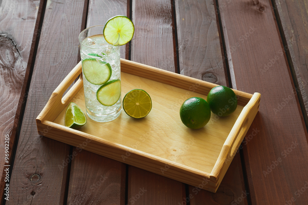 Drink on wooden tray with ice and condensation on glass