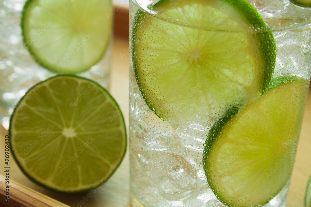 Two drinks on wooden tray with ice and condensation on glass