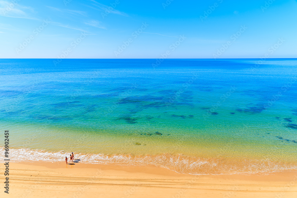 Unidentified women walking on Praia da Rocha beach along ocean in Portimao town, Algarve region, Portugal Unidentified women walking on Praia da Rocha beach along ocean in Portimao town, Algarve region, Portugal