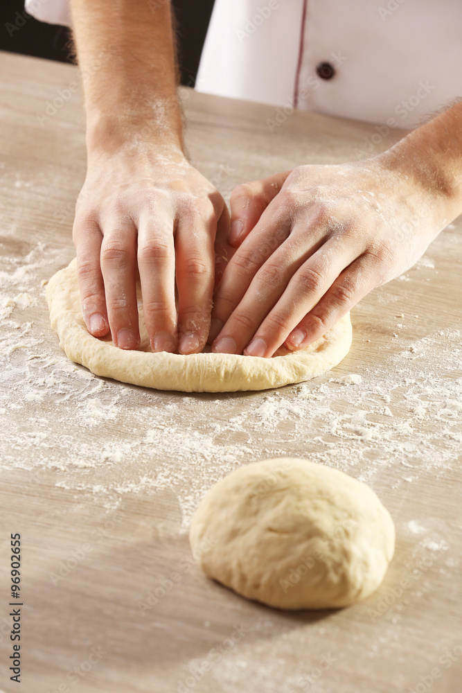 Hands kneading dough for pizza on the wooden table, close-up Hands kneading dough for pizza on the wooden table, close-up
