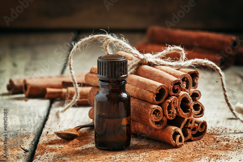 Картината върху платно Essential cinnamon oil in a small bottle, ground cinnamon and ci