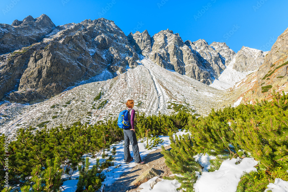 Young woman tourist looking at mountains covered with snow in autumn landscape of Hincova valley, Tatra Mountains, Slovakia