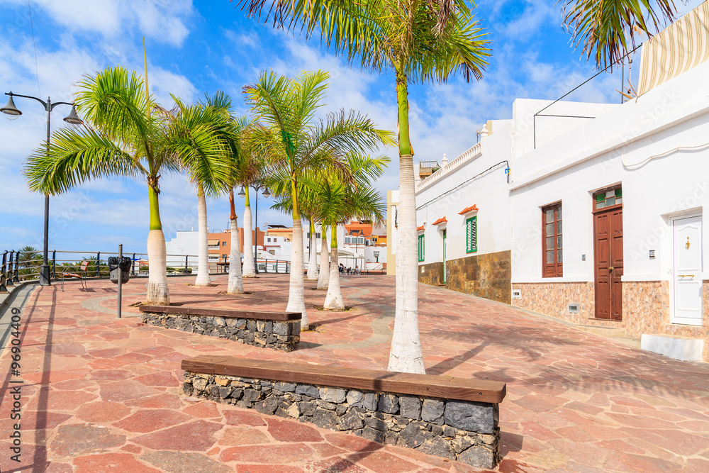 Palm trees on promenade in Alcala town with typical Canarian architecture on coast of Tenerife, Canary Islands, Spain