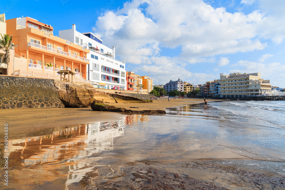 Reflection of El Medano town buildings in water on beach at sunrise, Tenerife, Canary Islands, Spain