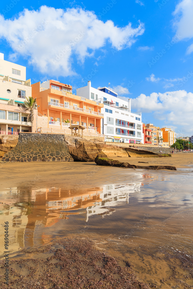 Reflection of El Medano town buildings in water on beach at sunrise, Tenerife, Canary Islands, Spain