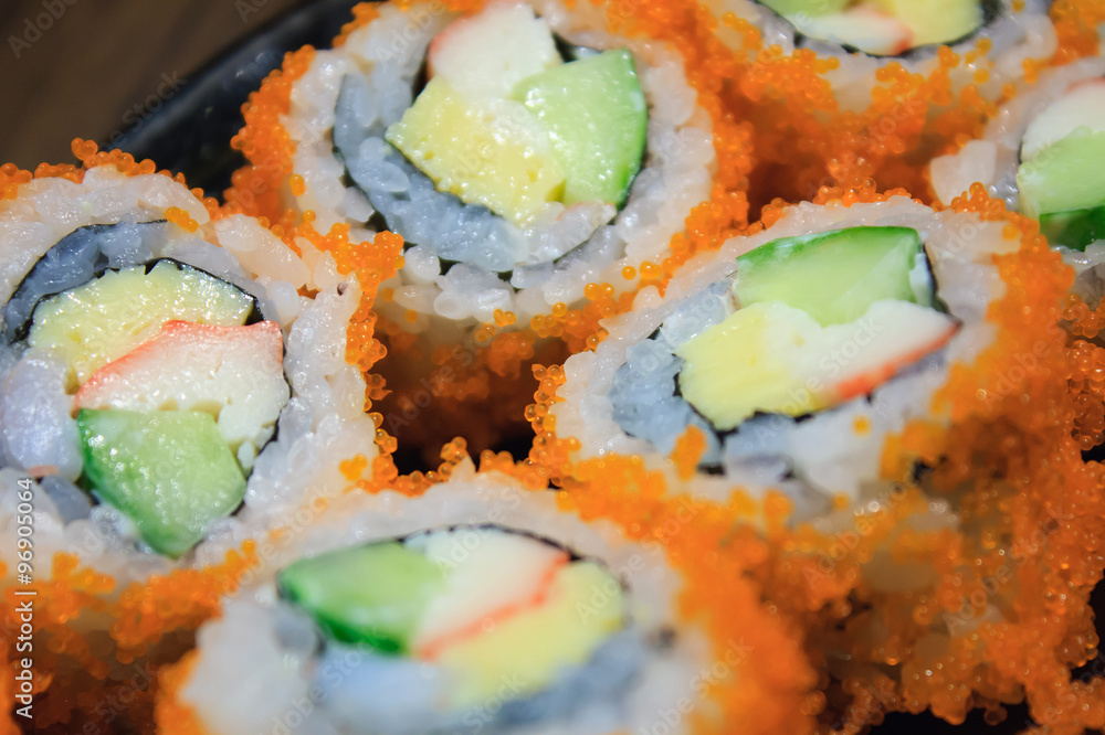 Sushi roll, row of California maki roll sushi with caviar on bla Sushi roll, row of California maki roll sushi with caviar on bla