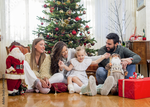 Family in front of Christmas tree, opening presents