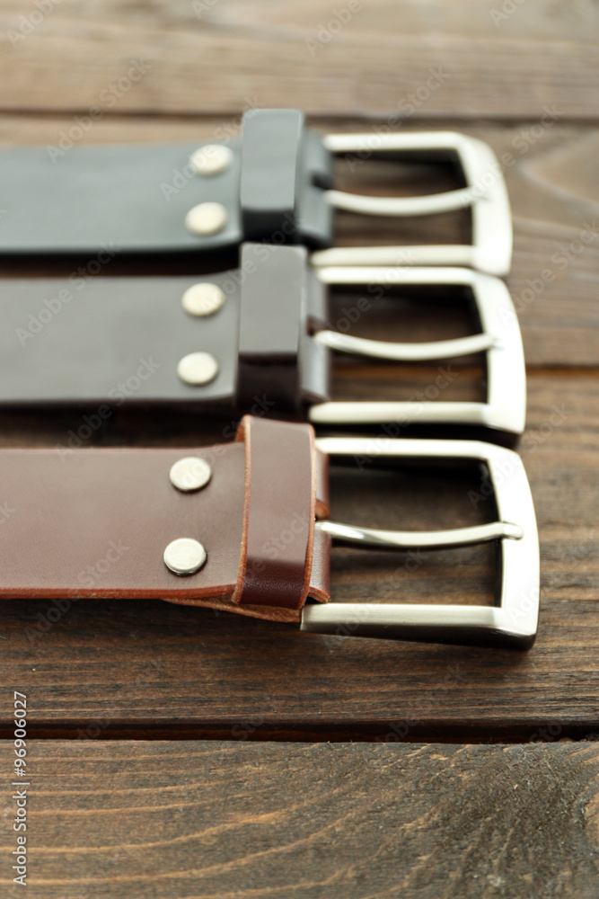 Leather belts with buckles on wooden background Leather belts with buckles on wooden background