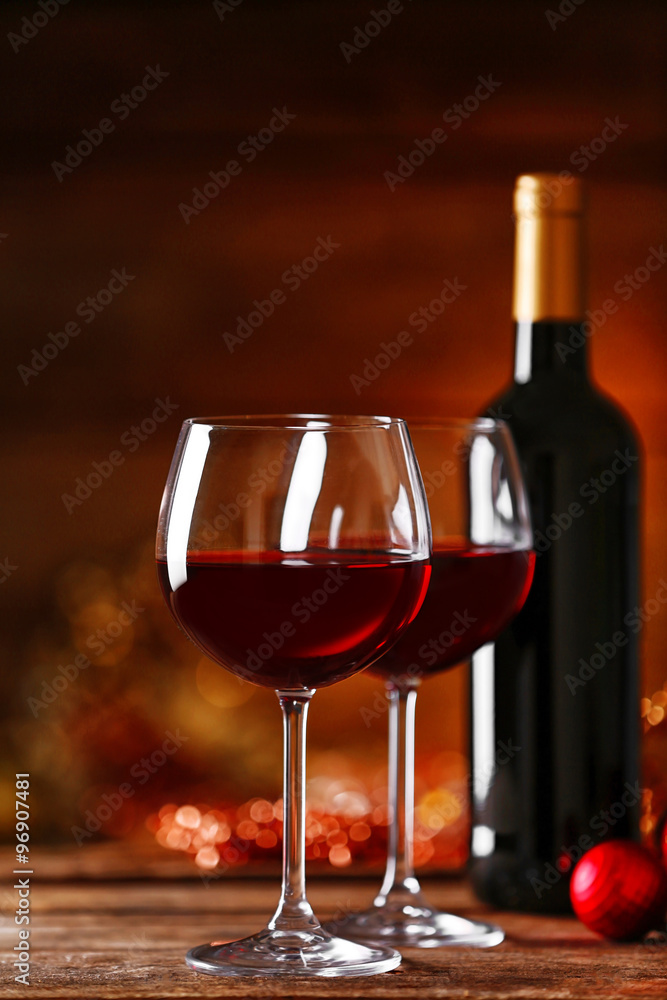 Red wine and Christmas ornaments on wooden table on wooden background