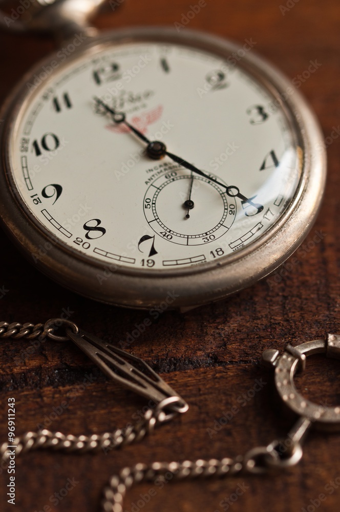orologio antico da tasca in argento con catenella appoggiato su tavolo di legno orologio antico da tasca in argento con catenella appoggiato su tavolo di legno