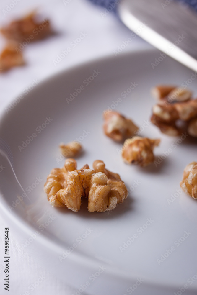 Walnuts on a white ceramic plate with blue napkin and knife. Walnuts on a white ceramic plate with blue napkin and knife.